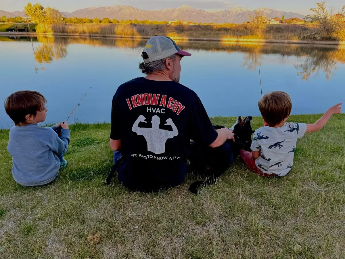 The owner of I Know A Guy HVAC with his two boys and their dog by a pond, the Wasatch Mountains behind them