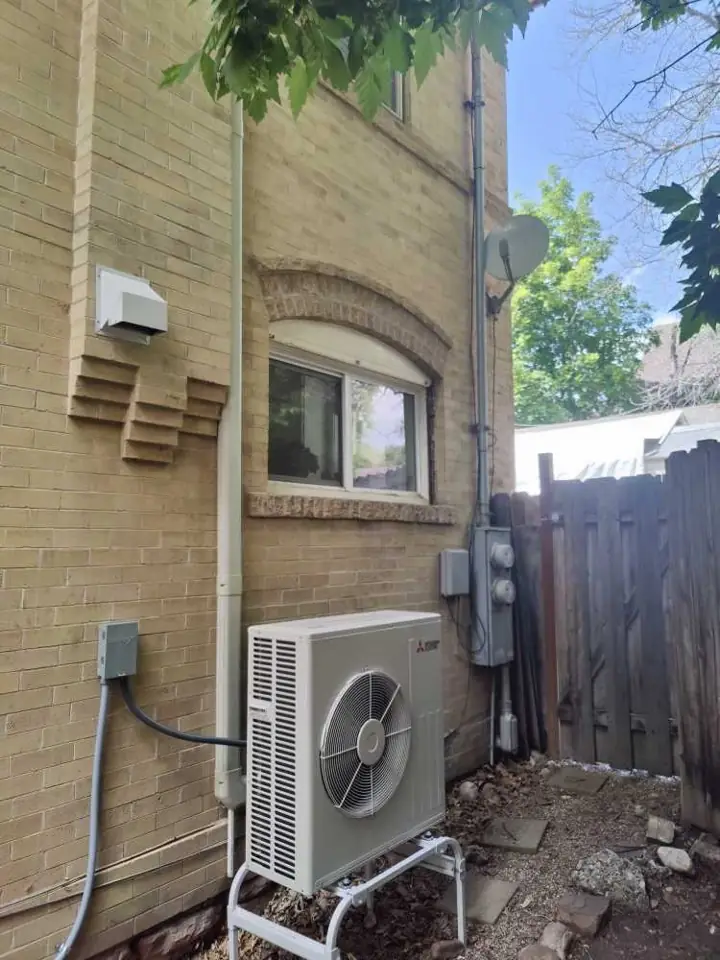 Mitsubishi ductless mini-split outdoor unit installed beside a brick home