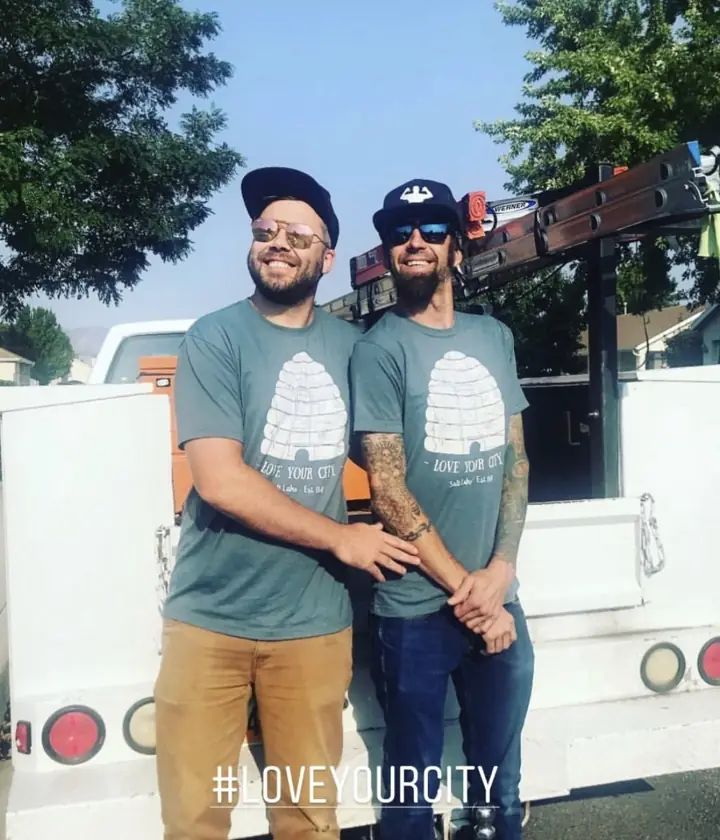 Two members of the I Know A Guy HVAC team smiling beside the company service truck