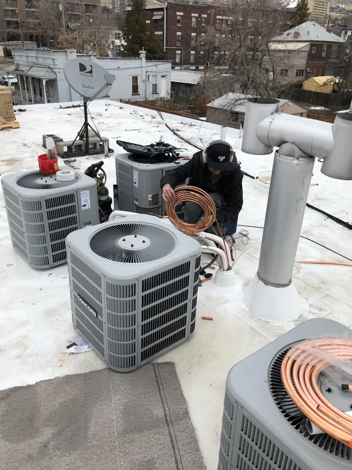 Technician setting new AC condensers on a Salt Lake City flat roof